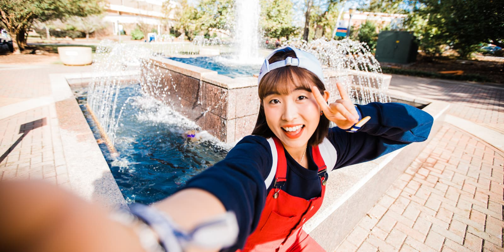 female student posing by the uwg fountain
