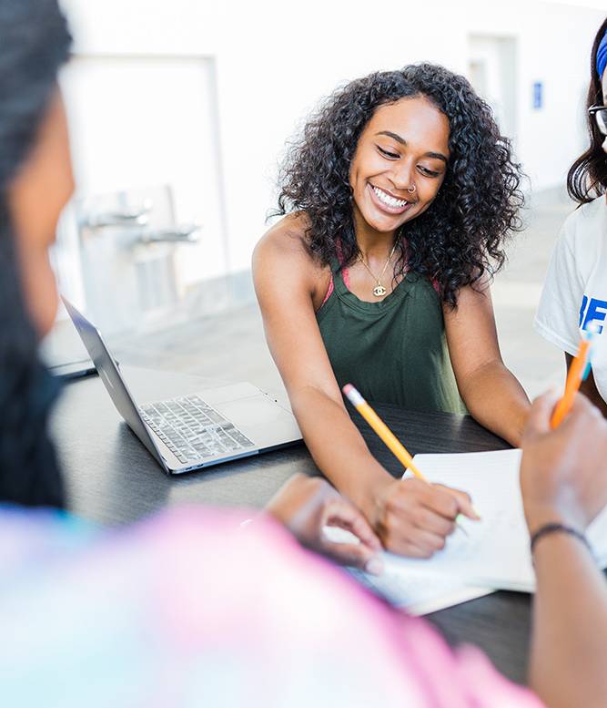 smiling female student outside with notebook