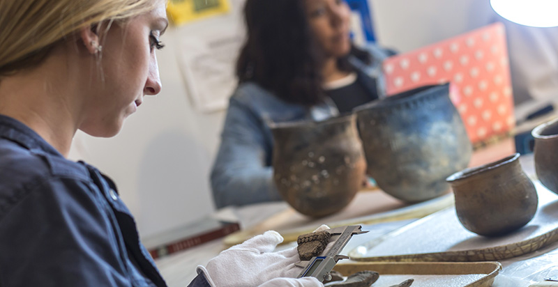 student and professor studying artifacts