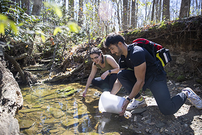 student taking water samples from creek
