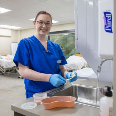 cna student brushing teeth in clinical lab