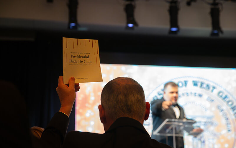 A celebrant bids on an auction item at 沙巴官网's Presidential Black Tie Gala