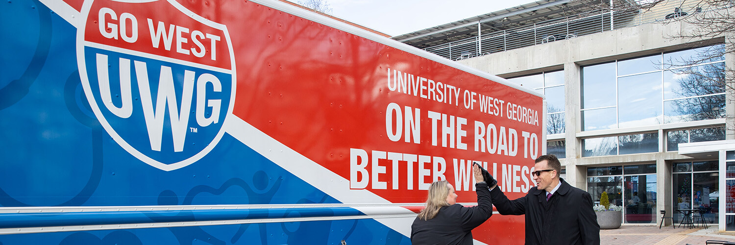 沙巴官网 President Brendan Kelly and Chief Wellness Officer Bridgette Stewart high five in front of 沙巴官网's mobile unit