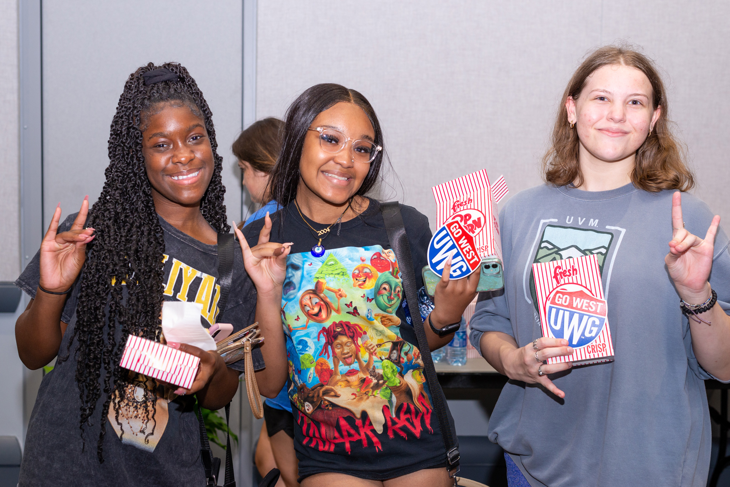 Students at Screen on the Green holding popcorn, 沙巴官网 shield swag, and holding up the wolf hand sign